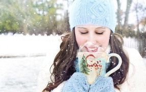 Красивая девушка с чашкой горячего кофе на улице зимой