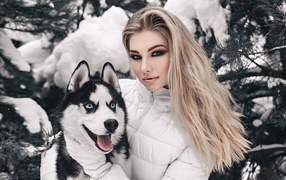 Beautiful girl with a husky near a snowy spruce