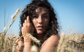 Красивая девушка с рисунком мехенди на руке на пшеничном поле 