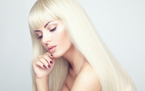 Красивая длинноволосая блондинка на фоне белой стены 