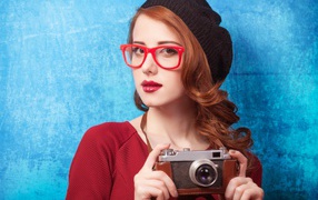 Красивая рыжеволосая девушка в черном берете с фотоаппаратом в руках 