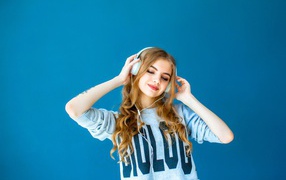 Beautiful young girl in headphones on a blue background