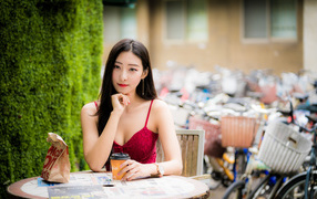 Милая девушка азиатка сидит за столиком в кафе