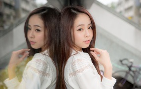 Милая азиатка в белой рубашке отражается в зеркальной поверхности 