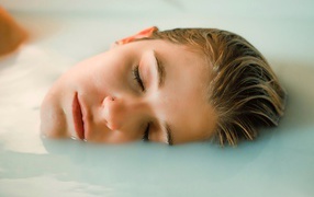 Девушка лежит с закрытыми глазами в ванной