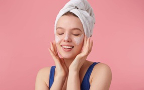 Девушка с полотенцем на голове мажет крем на лицо
