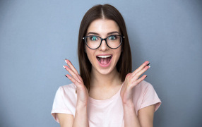 Joyful girl with glasses on a gray background