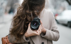 Длинноволосая девушка с фотоаппаратом в руках 