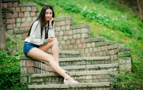 Длинноволосая девушка азиатка сидит на старых ступенях 