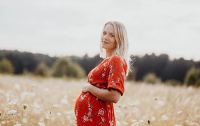 Pregnant girl in red dress on the field