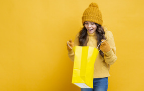 Smiling girl in a warm sweater with a package in her hands