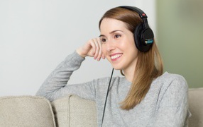 Smiling girl in headphones on sofa