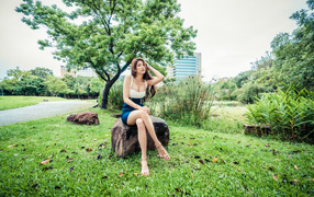 Spectacular Asian girl sits on a stone in the park