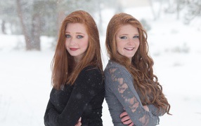 Две улыбающиеся рыжеволосые сестры на улице зимой 