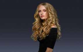 Молодая блондинка с красивыми длинными волосами в черном платье