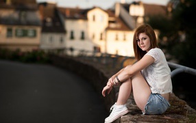 Молодая девушка с короткими  волосами сидит на улице