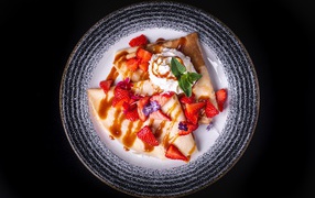 Thin crepes with cream on a plate with strawberries and syrup top view