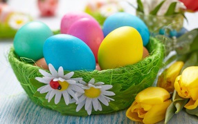Разноцветные яйца на столе с тюльпанами на Пасху