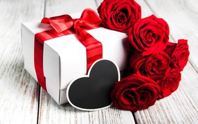 Bouquet of beautiful red roses on the table with a gift for your beloved on March 8