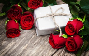 Bouquet of red roses on a table with a gift for March 8
