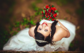 Smiling girl bride with a bouquet of red roses