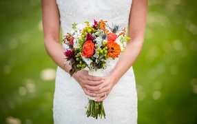 The bride's bouquet in the hands of a girl in a white wedding dress
