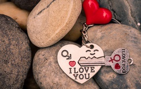 A heart-shaped keychain with a key lies on the stones