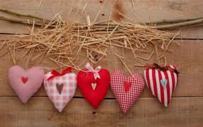 Fabric hearts on a table with hay and a branch