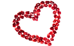 Heart made from pomegranate seeds on a white background