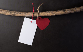 Red heart and white sheet of paper on a branch