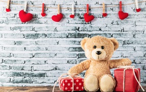 Медвежонок Тедди с подарками на фоне стены с сердечками