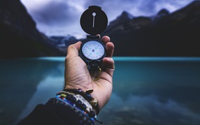 Compass in a man's hand against a background of mountains