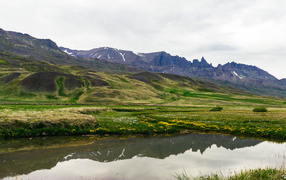 Озеро у холмов с зеленой травой в горах