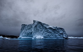 Large iceberg in the ocean under a cloudy sky