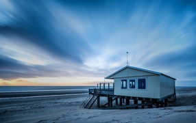 The lifeguard house stands on the beach under a beautiful sky