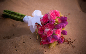 Beautiful bouquet of roses with tulips lies on the sand