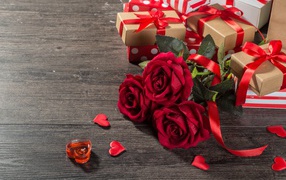 Bouquet of red roses and gifts on the table