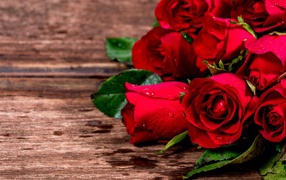 Bouquet of red roses on a wooden table in drops of water