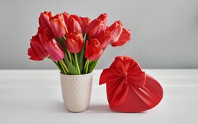 Букет красных тюльпанов на столе с коробкой в форме сердца