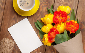 Bouquet of tulips on a table with a sheet of paper and a cup of coffee