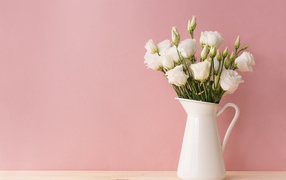 Bouquet of white eustoma in a vase on a pink background