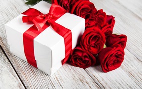 Red roses on a table with a gift with a red ribbon