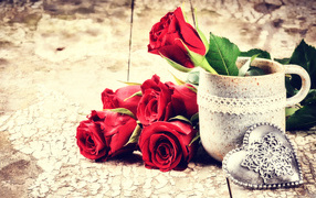 Red roses on a table with a mug and a heart