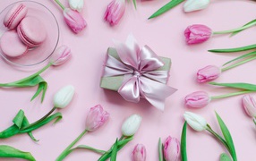Тюльпаны на розовом фоне с подарком и десертом макарон 