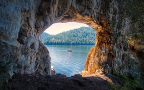 An archway in the rock leads to the lake