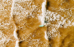 Белые волны на воде поднимают песок