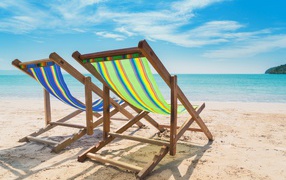 Two sun loungers stand on the sand at the beach in summer