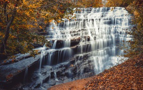 The fast water of the waterfall flows down the cascades of stones in autumn