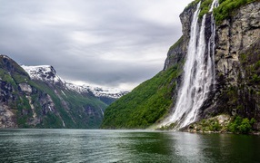 Waterfall flows down from a cliff into a lake, Norway