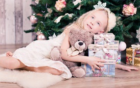 Beautiful blue-eyed girl with gifts by the Christmas tree